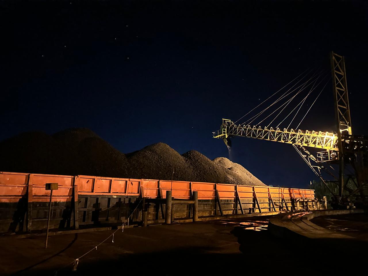 Coal stockpile and barge loader operating under the night sky